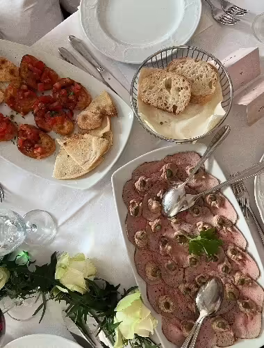 Antipasti-Platte mit Vitello Tonnato, Bruschetta und Brot auf weiß gedecktem Tisch im Restaurant Bei Peppino Würzburg