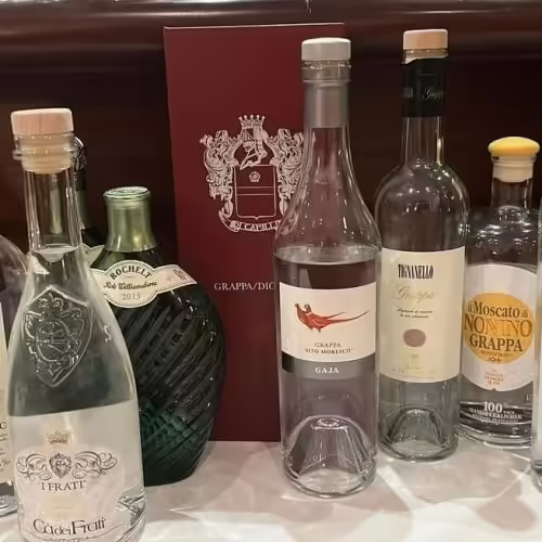 Mehrere Flaschen italienischer Grappa mit Etiketten und roter Grappakarte im Restaurant Bei Peppino Würzburg