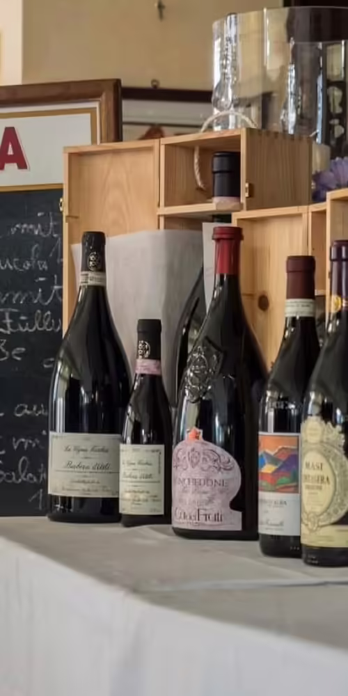 Auswahl italienischer Weine und Grappa auf Tisch vor Kreidetafel mit Tageskarte im Ristorante Bei Peppino Würzburg