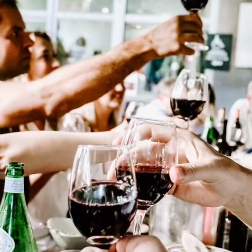 Gäste im Restaurant Bei Peppino stoßen mit Gläsern Rotwein an, Grill- und Weinabend in gemütlicher Würzburger Atmosphäre